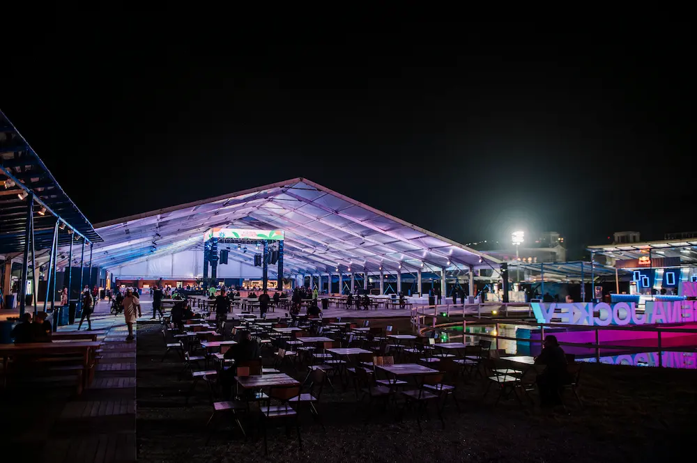 Circulação e área externa coberta com mesas, tenda e pista na edição anterior.